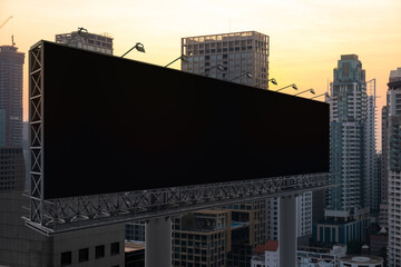 Blank black road billboard with Bangkok cityscape background at sunset. Street advertising poster, mock up, 3D rendering. Side view. The concept of marketing communication to promote or sell idea.