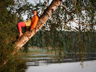 beautiful girl on a tree over water at sunset