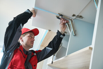 Furniture assembling. Professional worker installing wardrobe lifting mechanism