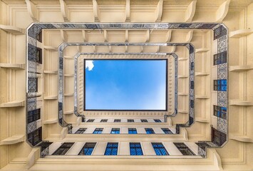 Low angle shot of a modern skyscraper forming a rectangle with a blue sky over it © Carlos Oyarzun/Wirestock
