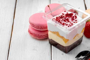 Creamy dessert in a plastic box on wooden table