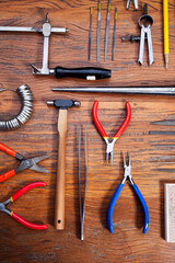 Different goldsmiths tools on the jewelry workplace. Desktop for craft jewelry making with...