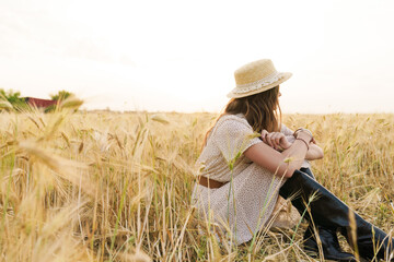 Naklejka na ściany i meble Photo of charming caucasian woman resting while sitting on wheat field