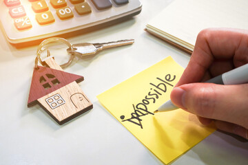 Yellow note with wording impossible with pen cross out on first 2 alphabets and house key chain...