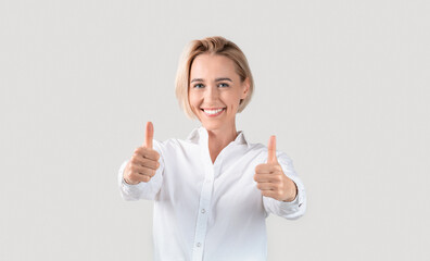 Cheerful business lady showing thumbs up gesture on light background