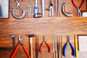 Different goldsmiths tools on the jewelry workplace. Desktop for craft jewelry making with professional tools.