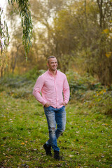 Naklejka na ściany i meble Portrait of a strong man in jeans and a pink shirt.
