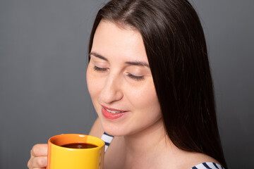 Portrait of a young woman with a coffee mug. Closeup of a beautiful girl is drinking coffee.