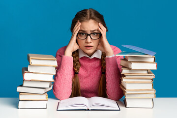 Exam preparation. Teen girl holding head among books