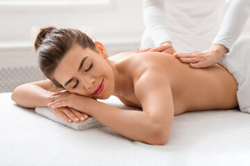 Obraz na płótnie Canvas Relaxed woman getting healing body massage at spa