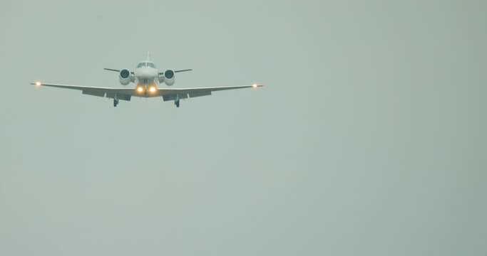 A light plane lands at the airport. The plane with the light on flies over the frame against the blue sky.