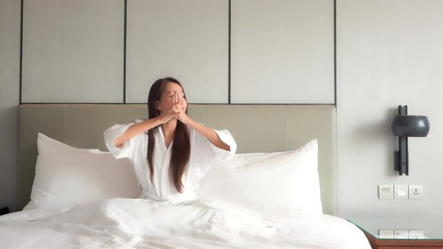 Asian model waking up at a luxury hotel bed space