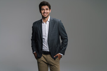 Photo of pleased businessman in jacket posing and smiling at camera