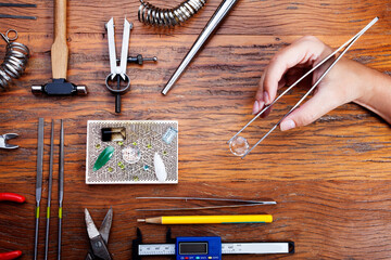 Different goldsmiths tools on the jewelry workplace. Desktop for craft jewelry making with...