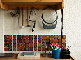 Different goldsmiths tools on the jewelry workplace. Desktop for craft jewelry making with professional tools. Set of tools over rustic wooden background.