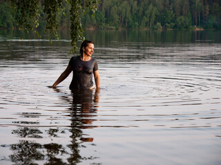 beautiful girl bathes in a lake at sunset