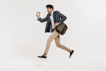 Fototapeta na wymiar Photo of young businessman drinking coffee while running with bag