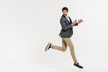 Photo of young businessman using cellphone while running with bag