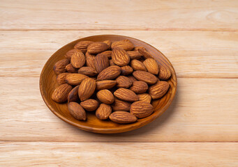 almonds in wood plate on pine wood table .