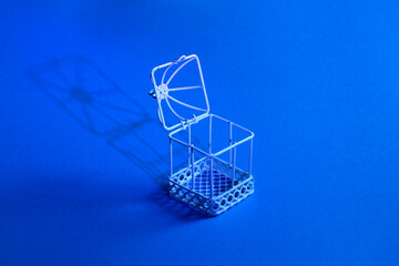 White metal cage with open door, blue background.