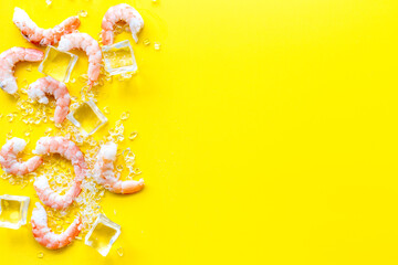 Shrimps - peeled, with ice - on yellow background frame copy space