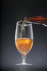 Beer pouring into glass on black background