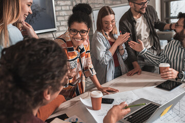 Group of modern business people in casual wear discussing architectural design in the creative office.