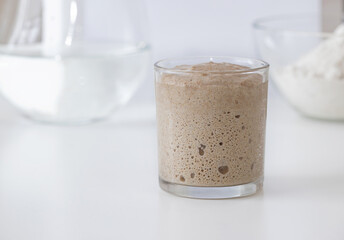 Sourdough bread in a glass Water and flour in the background