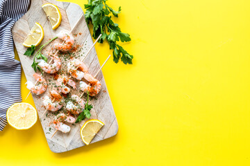 Shrimp skewers - appetizer in mediterranean kitchen - on yellow table top view copy space