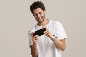 Portrait of unshaven excited man playing online game on mobile phone
