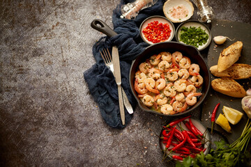 Grilled shrimps in cast iron grilling pan with fresh lemon, parsley, chili, garlic white wine sauce