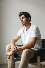 Portrait of confident man posing on camera while sitting on armchair