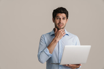 Portrait of confused man looking at camera while using computer
