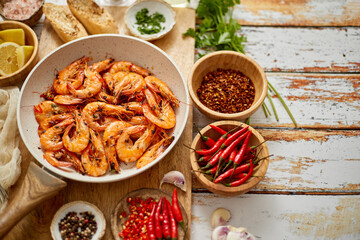 Top view of prawns shrimps roasted on pan with herbs placed on rustic wooden kitchen table