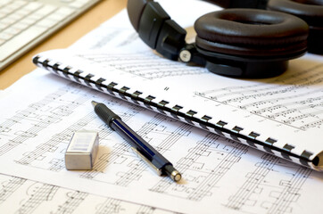 Classical sheet music on desk with mechanical pencil, eraser and headphones