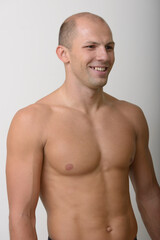 Happy young muscular bald man thinking shirtless