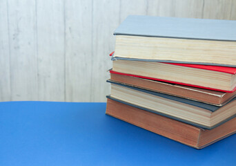 Old and well used hardback books. Back to school. Many Books Piles. Hardback books on blue table. Stack of colorful books. Side view. Copy space for text