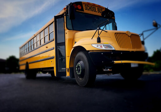 Low angle view of the front door side entrance of a yellow American public school bus used to transport kids to school, field trips and extra circular events such as sports teams.