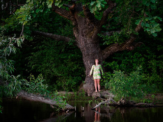 Fototapeta na wymiar girl by the old oak tree by the lake