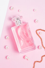 pink perfume bottle with pearls and a gold chain on a pink sheet on a white background copy space. top view, mockup