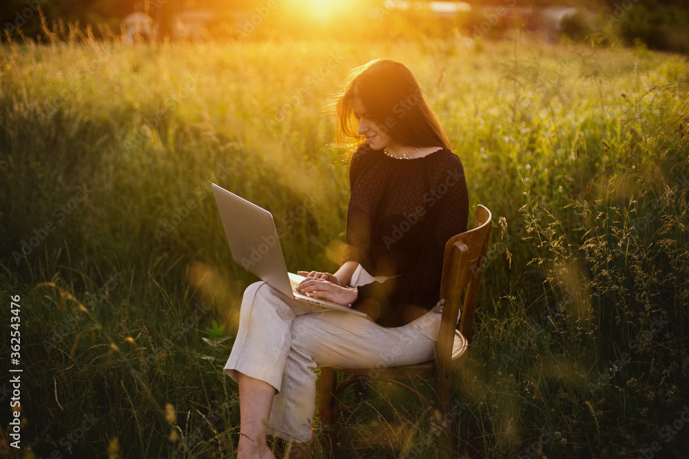 Wall mural freelance and remote work outdoors. creative image. fashionable elegant girl with laptop sitting on 