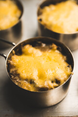 Julienne with chicken, cheese and mushrooms served in small metal bowl. Selective focus. Shallow depth of field.