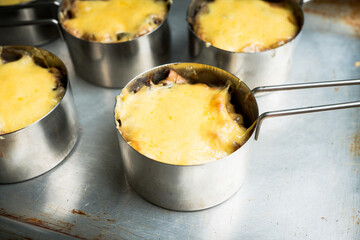 Julienne with chicken, cheese and mushrooms served in small metal bowl. Selective focus. Shallow depth of field.