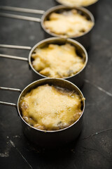 Julienne with chicken, cheese and mushrooms served in small metal bowl. Selective focus. Shallow depth of field.