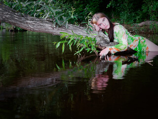 girl lies in the water on a branch of an old tree