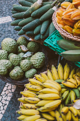 Exotic fruit in baskets and crates. Bananas, annona, cherimola, banana passionfruit.
