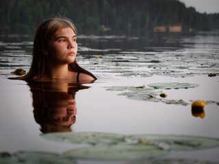 Fototapeta premium mermaid girl in the water among water lilies at sunset