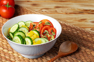 Ceramic bowl of tomato and cucumber salad on table