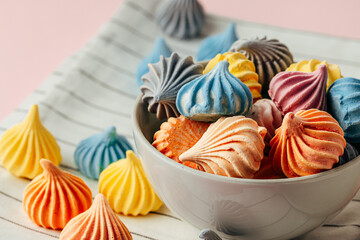 Colorful meringue cookies on pink surface close up