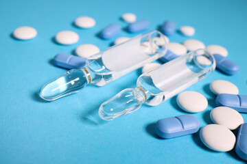 Fototapeta na wymiar blue and white pills on a blue background with transparent ampoules